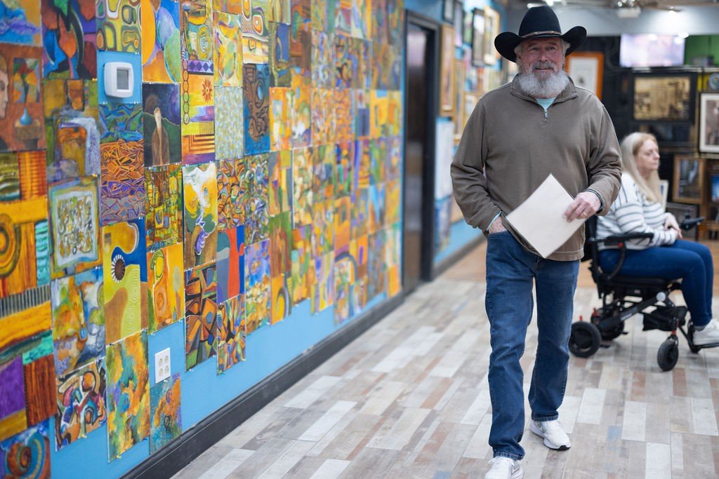 Guest walking past a wall of colorful paintings