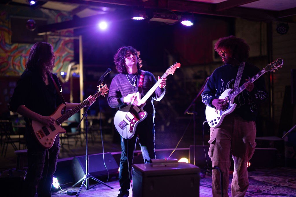 Three young musicians playing guitars on stage